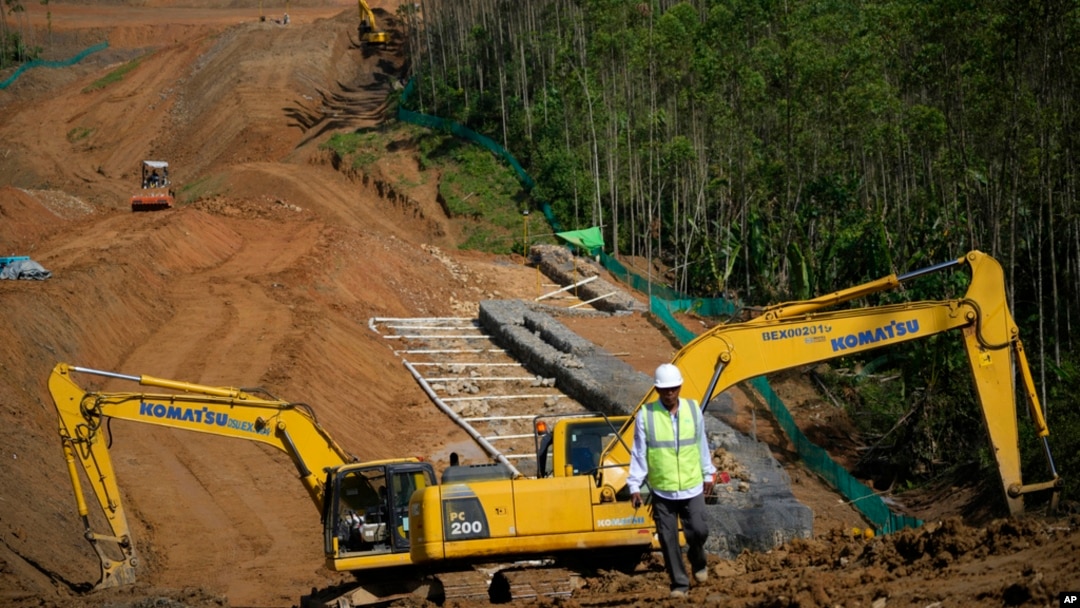 Para pekerja berjalan di dekat alat berat di lokasi pembangukan IKN di Kabupaten Penajam Paser Utara, di Kalimantan Timur, 8 Maret 2023. LSM Auriga Nusantara melaporkan pembangunan IKN menyebabkan meningkatnya deforestasi di Kalimantan. (Foto: Achmad Ibrahim/AP Photo)