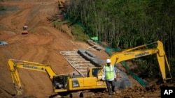 Para pekerja berjalan di dekat alat berat di lokasi pembangukan IKN di Kabupaten Penajam Paser Utara, di Kalimantan Timur, 8 Maret 2023. LSM Auriga Nusantara melaporkan pembangunan IKN menyebabkan meningkatnya deforestasi di Kalimantan. (Foto: Achmad Ibrahim/AP Photo)