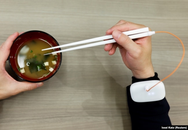 FILE - An employee of Kirin Holdings demonstrates chopsticks that can enhance food taste in Tokyo, Japan April 15, 2022. (REUTERS/Issei Kato)