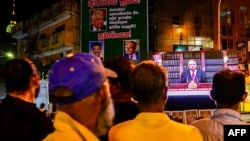 People watch a live telecast as Sri Lanka's President Ranil Wickremesinghe addresses the nation in Colombo, June 26, 2024. The country has clinched a restructuring deal with a majority of bilateral lenders covering up to $5.8 billion in debt.