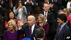 U.S. President Joe Biden, accompanied by first lady Jill Biden, waves as he arrives to speak at the Canadian Parliament, March 24, 2023, in Ottawa, Ontario. Canadian Prime Minister Justin Trudeau looks on at right.