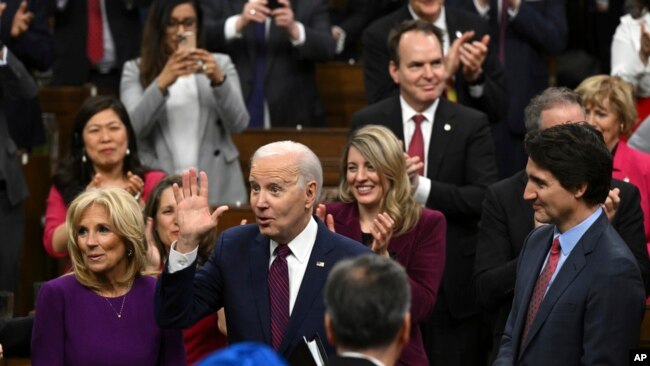 U.S. President Joe Biden, accompanied by first lady Jill Biden, waves as he arrives to speak at the Canadian Parliament, March 24, 2023, in Ottawa, Ontario. Canadian Prime Minister Justin Trudeau looks on at right.