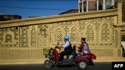 FILE - This picture taken July 16, 2023, shows Uyghur people riding a trike scooter in Kashgar city in northwestern China's Xinjiang region.