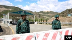 FILE - Guards stand at an Azerbaijani checkpoint set up at the entry of the Lachin corridor, the Armenian-populated breakaway Nagorno-Karabakh region's only land link with Armenia, by a bridge across the Hakari river, on May 2, 2023. 