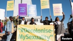 FILE - People hold banners in support of LGBTQ+ rights outside the Namibian high court, which made a landmark ruling in favor of LGBTQ+ communities in Windhoek on June 21, 2024. Advocates say people who identify as LGBTQ+ have difficulty getting health care in Namibia.