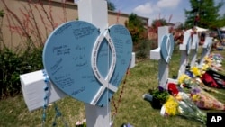 In this May 8, 2023, photo, a cross with a name Christian LaCour written at the center, stands by others representing each of the victims of a mass shooting at a makeshift memorial in Allen, Texas.