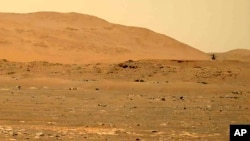 Penjelajah Mars Perseverance menunjukkan helikopter Ingenuity, kanan, terbang di atas permukaan planet. (Foto: NASA via AP)