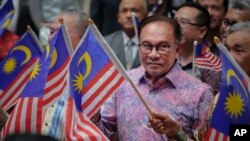 Perdana Menteri Malaysia Anwar Ibrahim mengibarkan bendera nasional usai menyampaikan pidato Hari Nasional di pusat konvensi di Putrajaya, Malaysia Rabu, 30 Agustus 2023. (AP/Vincent Thian)