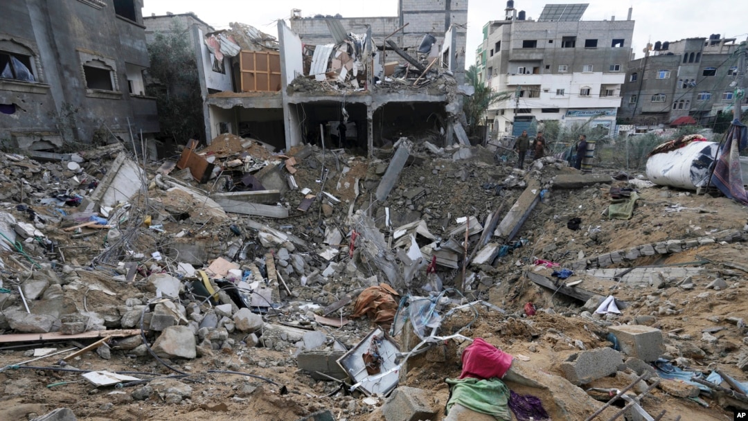 Beberapa warga Palestina memeriksa kehancuran setelah serangan udara Israel di sebuah bangunan permukiman di kota Deir al Balah, Jalur Gaza, 14 Januari 2024.