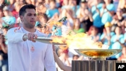 Greek Olympic medalist Ioannis Fountoulis lights the caldron with the Olympic Flame during the Olympic flame handover ceremony at Panathenaic stadium, where the first modern games were held in 1896, in Athens, April 26, 2024. 