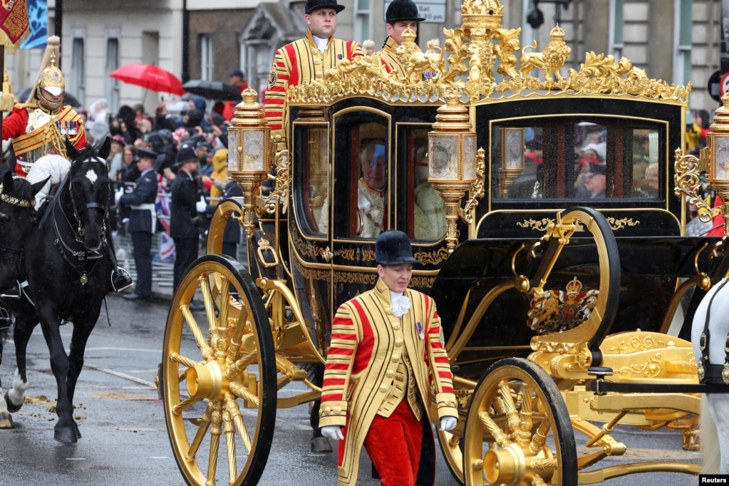 Los reyes miran a través de la ventanilla del coche mientras pasan frente al Big Ben en Westminster.