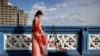 FILE - A Chinese student who calls herself Evie makes a video for her followers on Douyin, a Chinese social media network, on Tower Bridge in London, March 25 2023. In late May 2024, Douyin announced a new verification mechanism for suspected fake content.