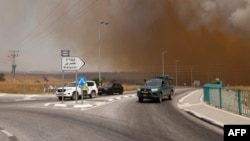Kendaraan meninggalkan daerah yang diselimuti asap akibat kebakaran setelah roket yang diluncurkan dari Lebanon selatan menghantam daerah di Dataran Tinggi Golan yang dianeksasi Israel, 4 Juli 2024. (Jalaa MAREY / AFP)