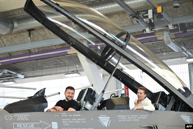 FILE - Ukrainian President Volodymyr Zelenskyy, left, and Danish Prime Minister Mette Frederiksen sit in a F-16 fighter jet in the hangar of the Skrydstrup Airbase in Vojens, northern Denmark, on Aug. 20, 2023.