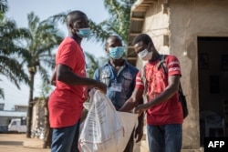 FILE - Agents distribute mosquito nets door-to-door on April 28, 2020, in Pahou, Benin, during a campaign aimed at fighting malaria.