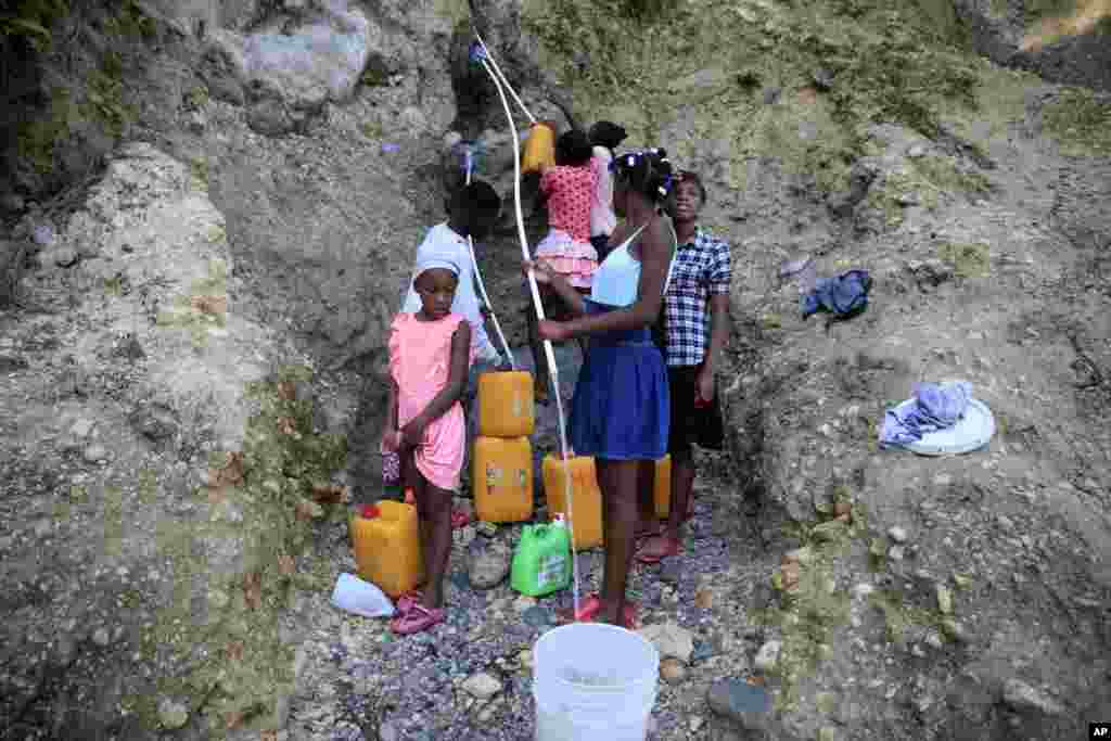 Ciudadanos de Puerto Príncipe, en Haití, también viven la falta de agua y llenan baldes de la que logran tomar de lo que sale de un barranco.&nbsp;