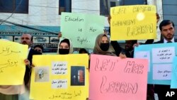 FILE - Afghan university students in Quetta, Pakistan, chant slogans and hold placards during a protest against the ban on university education for women in their home country, Dec. 24, 2022. 