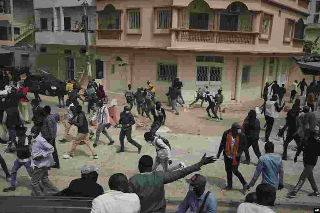 People run from tear gas thrown by riot police after the opposition leader&#39;s Ousmane Sonko left the tribunal in Dakar, Senegal, Thursday, February 16, 2023. Police in Senegal smashed out the windows of the Sonko&#39;s car and forced him from the vehicle after he appeared in court