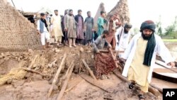 Warga berkumpul untuk membereskan puing-puing rumah yang hancur akibat longsor yang timbul setelah hujan deras melanda distrik Surkhroad di provinsi Nangarhar, Afghanistan, pada 15 Juli 2024. (Foto: AP/Shafiullah Kakar)