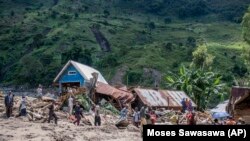 Warga berjalan di samping rumah yang hancur akibat banjir di Desa Nyamukubi, Provinsi Kivu Selatan, di Kongo, Sabtu, 6 Mei 2023.(AP/Moses Sawasawa)