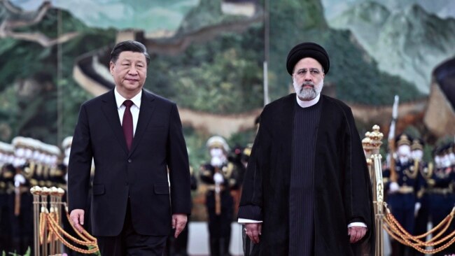 In this photo released by Xinhua News Agency, visiting Iranian President Ebrahim Raisi, right, walks with Chinese President Xi Jinping after reviewing an honor guard during a welcome ceremony at the Great Hall of the People in Beijing, Feb. 14, 2023