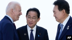 U.S. President Joe Biden, left, talks with Japan's Prime Minister Fumio Kishida and South Korean President Yoon Suk Yeol, right, ahead of a trilateral meeting on the sidelines of the G7 Summit in Hiroshima, Japan, May 21, 2023.