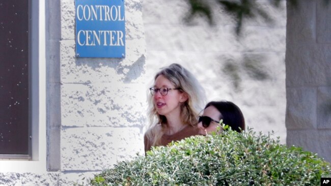 Elizabeth Holmes, left, is escorted by prison officials into a federal women’s prison camp on May 30, 2023, in Bryan, Texas. Holmes will spend the next 11 years serving her sentence for overseeing a blood-testing hoax at Theranos.