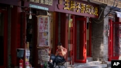 FILE - A Chinese man sits outside convenience store in Beijing, July, 26, 2024. 