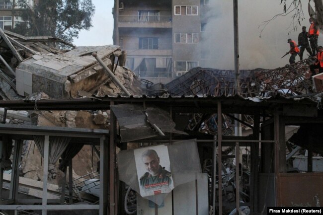 Foto mendiang komandan militer senior Iran, Jenderal Qassem Soleimani, terpampang di antara puing-puing di konsulat Iran di ibu kota Suriah, Damaskus, 1 April 2024. (Foto: REUTERS/Firas Makdesi)