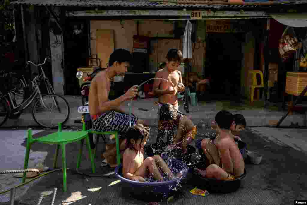 Children sit in buckets and basins during a hot day in Manila, Philippines.