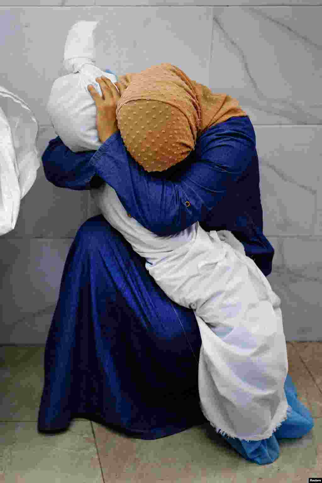 Palestinian woman Inas Abu Maamar, 36, embraces the body of her 5-year-old niece Saly, who was killed in an Israeli strike, at Nasser hospital in Khan Younis in the southern Gaza Strip, Oct.17, 2023. 