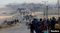 Palestinians, who were displaced by Israel's military offensive on south Gaza, make their way as they attempt to return to their homes in north Gaza through an Israeli checkpoint, as seen from central Gaza Strip April 15, 2024. 