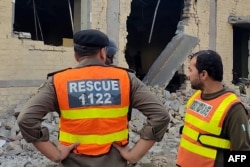 Rescuers stand at the site of an attack after militants rammed an explosive-laden vehicle into a Pakistan military base, in the town of Daraban of Dera Ismail Khan district, in Khyber Pakhtunkhwa province, on Dec. 12, 2023.