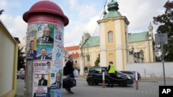 Campaign posters of various candidates running Sunday in Poland's crucial parliamentary elections are displayed in Sandomierz, Poland, Oct. 13, 2023. 