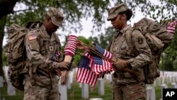 Miembros del Tercer Regimiento de Infantería de Estados Unidos, conocido como La Vieja Guardia, instalan banderas norteamericanas frente a las lápidas del Cementerio Nacional de Arlington, el pasado 25 de mayo de 2023.