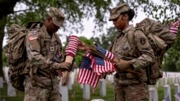 Miembros del Tercer Regimiento de Infantería de Estados Unidos, conocido como La Vieja Guardia, instalan banderas norteamericanas frente a las lápidas del Cementerio Nacional de Arlington, el pasado 25 de mayo de 2023.