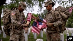 Members of the 3rd U.S. Infantry Regiment put flags in front of each headstone at Arlington National Cemetery in Arlington, Virginia, on May 25, 2023, to honor the nation's fallen military heroes ahead of Memorial Day.