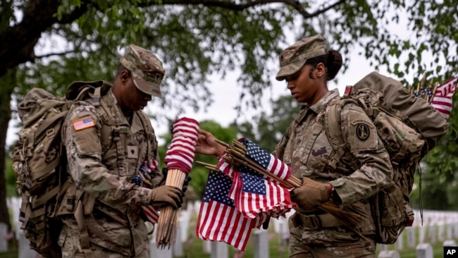 Members of the 3rd U.S. Infantry Regiment, also known as The Old Guard, place flags in front of each headstone at Arlington National Cemetery in Arlington, Virginia, May 25, 2023, to honor fallen U.S. service members ahead of Memorial Day.