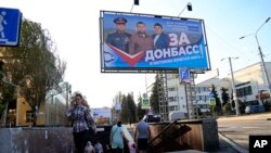 People walk out from an underground crossing decorated with a United Russia party poster that reads: "For Donbas where you want to live!" prior to local elections in Donetsk, the capital of Russian-controlled Donetsk region, eastern Ukraine, Sept. 7, 2023