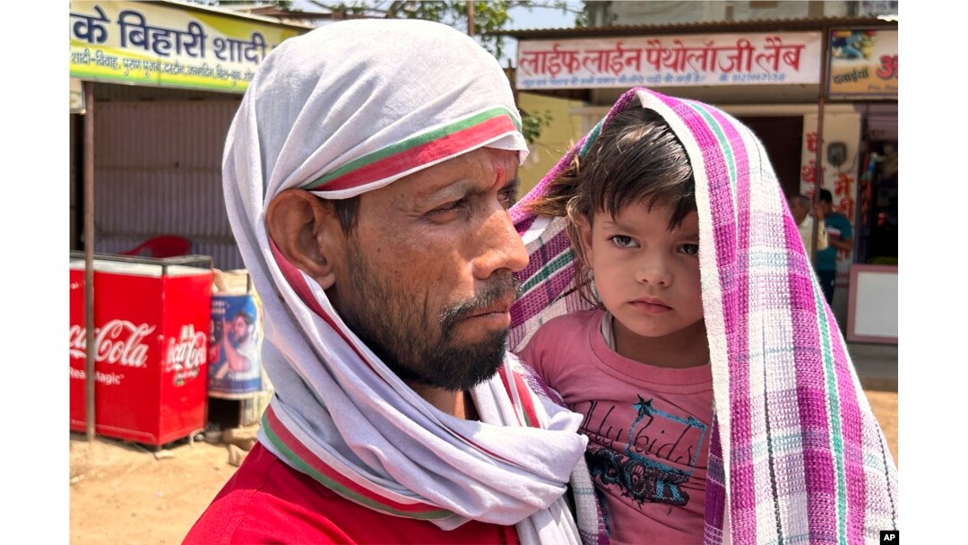 Seorang pria berjalan menggendong seorang anak yang ditutupi syal untuk melindungi diri dari panas yang menyengat di Lalitpur, negara bagian Uttar Pradesh, India, Sabtu, 17 Juni 2023. (AP/Rajesh Kumar Singh)