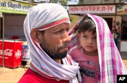 Seorang pria berjalan menggendong seorang anak yang ditutupi syal untuk melindungi diri dari panas yang menyengat di Lalitpur, negara bagian Uttar Pradesh, India, Sabtu, 17 Juni 2023. (AP/Rajesh Kumar Singh)