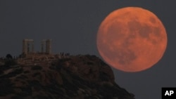 The supermoon rises behind the ancient temple of Poseidon at Cape Sounion, about 70 kilometers (45 miles) south of Athens, Greece, Wednesday, Aug. 30, 2023. (AP Photo/Thanassis Stavrakis)