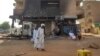 Des hommes passent devant une banque incendiée dans le sud de Khartoum, le 24 mai 2023.