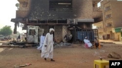 Des hommes passent devant une banque incendiée dans le sud de Khartoum, le 24 mai 2023.