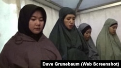 สตรีชาวมุสลิมละหมาดหกโมงเย็น ในเทศกาลดนตรีแฮมเมอร์โซนิก อินโดนีเซีย (screenshot from Dave Grunebaum's Heavy metal music finds a home in Indonesia, VOA)