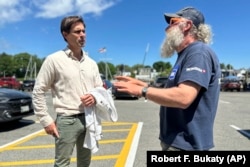 Tom Hedstrom, chair of the Select Board, speaks with schooner captain Aaron Lincoln during a visit to the harbor, Tuesday, June 4, 2024, in Camden, Maine. (AP Photo/Robert F. Bukaty)