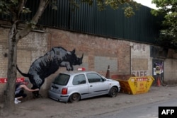 An artwork by Banksy, the eighth to released in eight days, depicts a rhino mounting a car, on a wall in Charlton, London, Aug. 12, 2024. The artist confirmed ownership of the work after posting an image of it on the social media app Instagram.