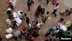 FILE - Outside Hong Kong's Sheung Shui train station, mainland Chinese visitors to Hong Kong in August 2012 transport boxes of instant noodles and packages of diapers to be parallel imported into Shenzhen for resale.