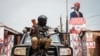 FILE - A police officer sits on a car at the gate of the headquarters of National Unity Platform in Kampala, Uganda, Jan. 18, 2021. 