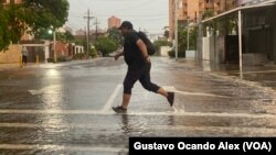 Un hombre trata de saltar un charco en la calle 72 de Maracaibo, Zulia, durante un chubasco, la mañana del pasado 2 de junio de 2023. Las autoridades prevén más chubascos y fuerte oleaje en los próximos días en Venezuela por el paso de la tormenta tropical Bret.